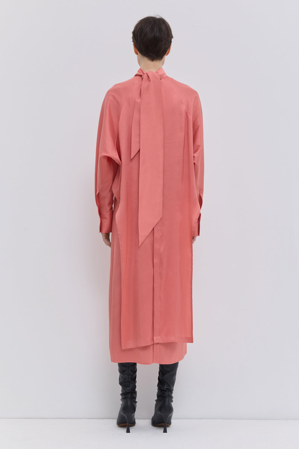 Back view of coral silk dress with long scarf detail and flowing silhouette