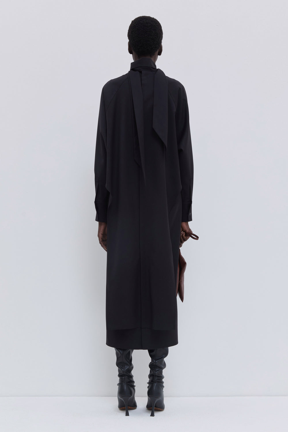 Side view of a black midi dress in 100% virgin wool with fluid silhouette.