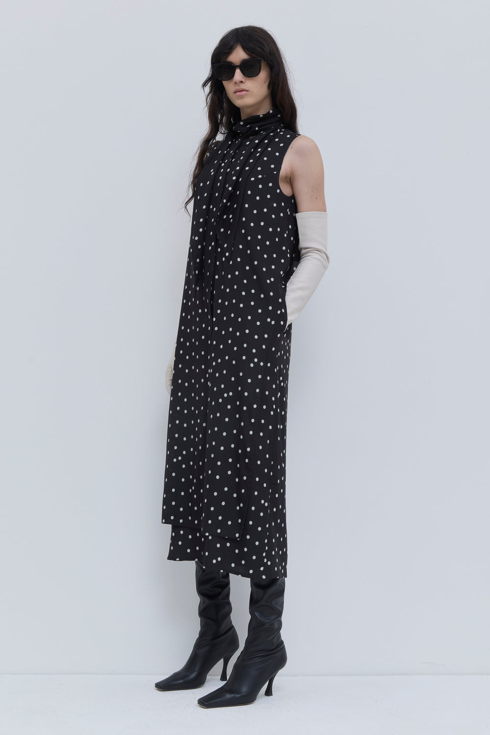 Side view of a black lady bug print dress with scarf neckline, sleeveless design and fluid double-layer construction by Christian Wijnants.