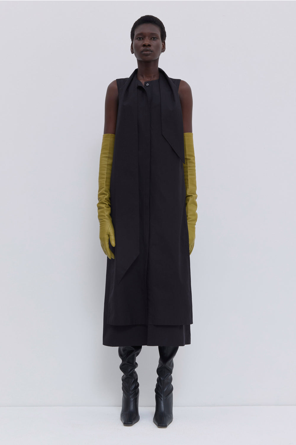 Side view of a black sleeveless cotton dress with asymmetric scarf, clean lines and relaxed silhouette by Christian Wijnants.