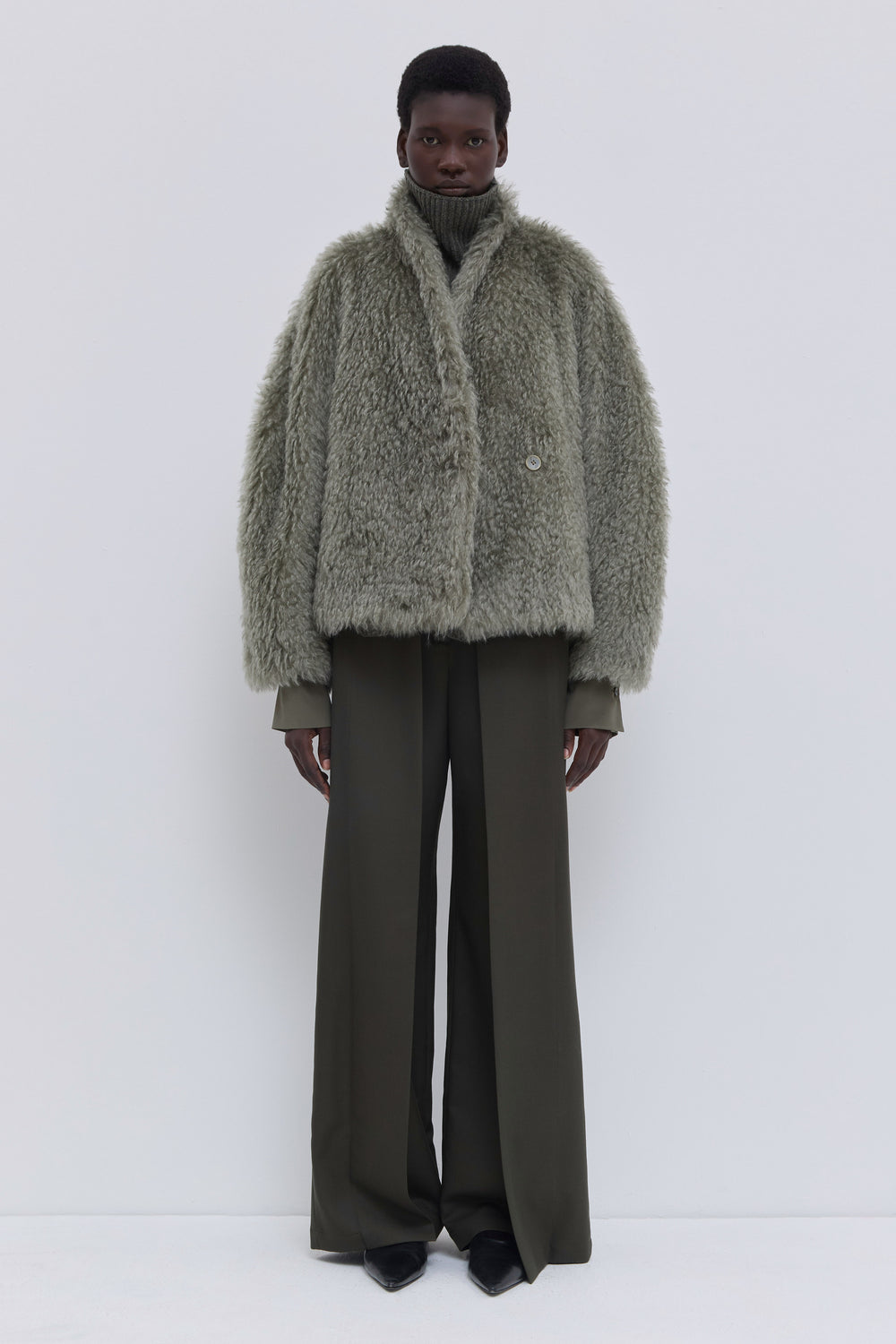 Front view of a sage faux fur jacket with soft shawl collar and relaxed fit.