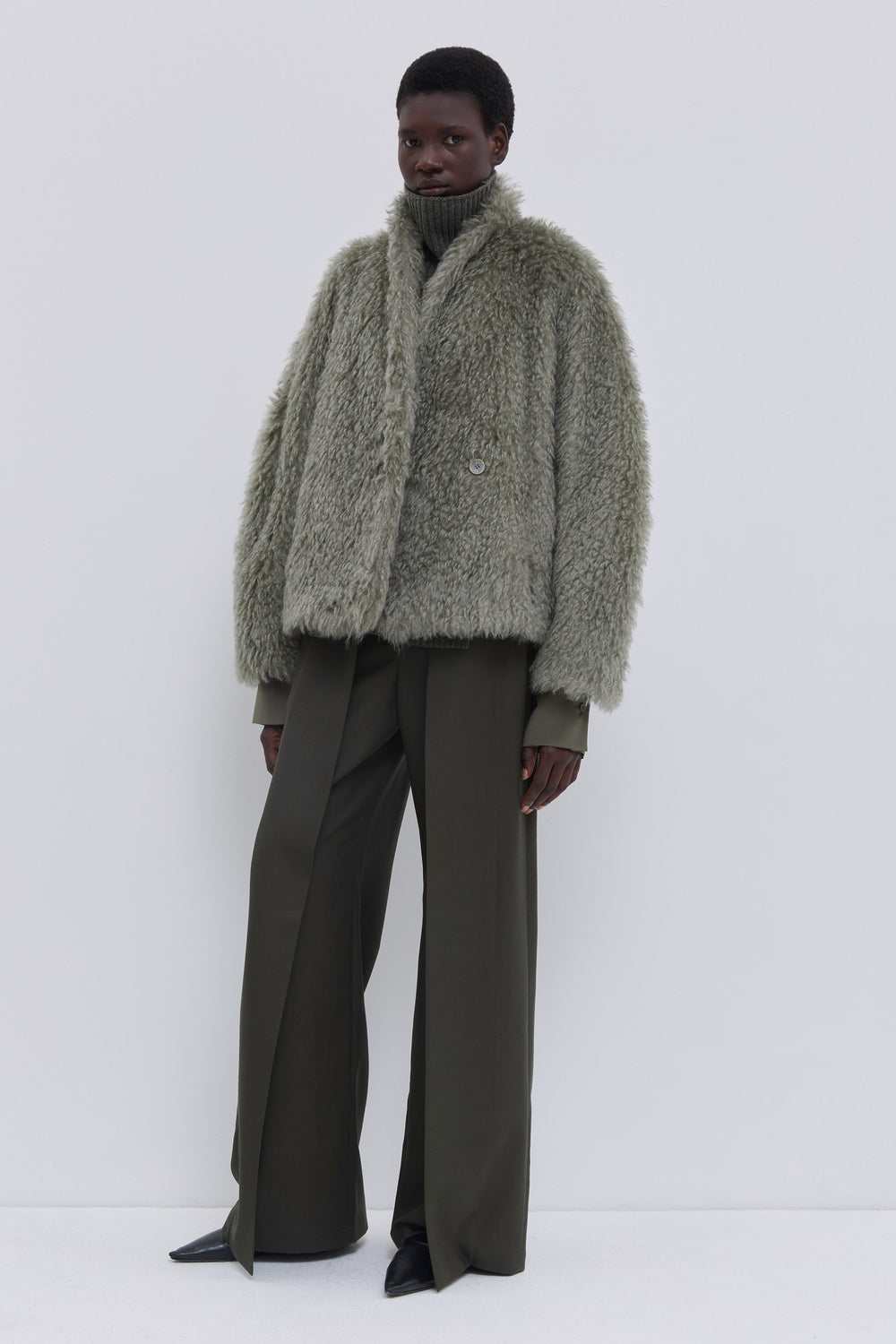 Side view of a sage Steiff faux fur jacket with oversized silhouette.