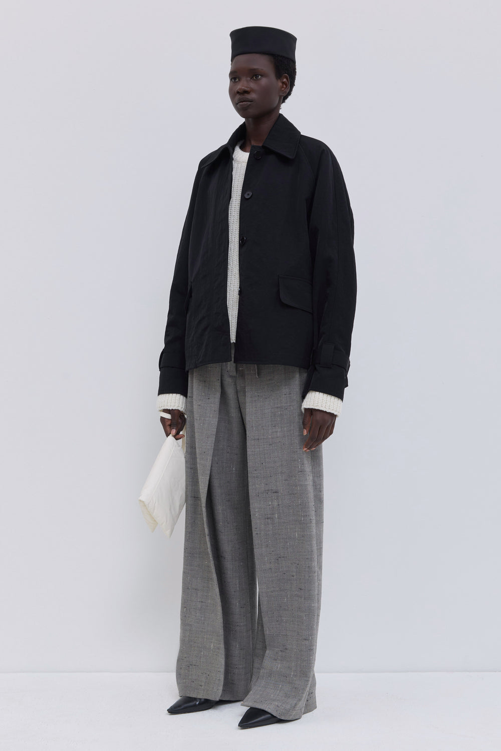 Front view of a black collared jacket with concealed button closure and relaxed fit.