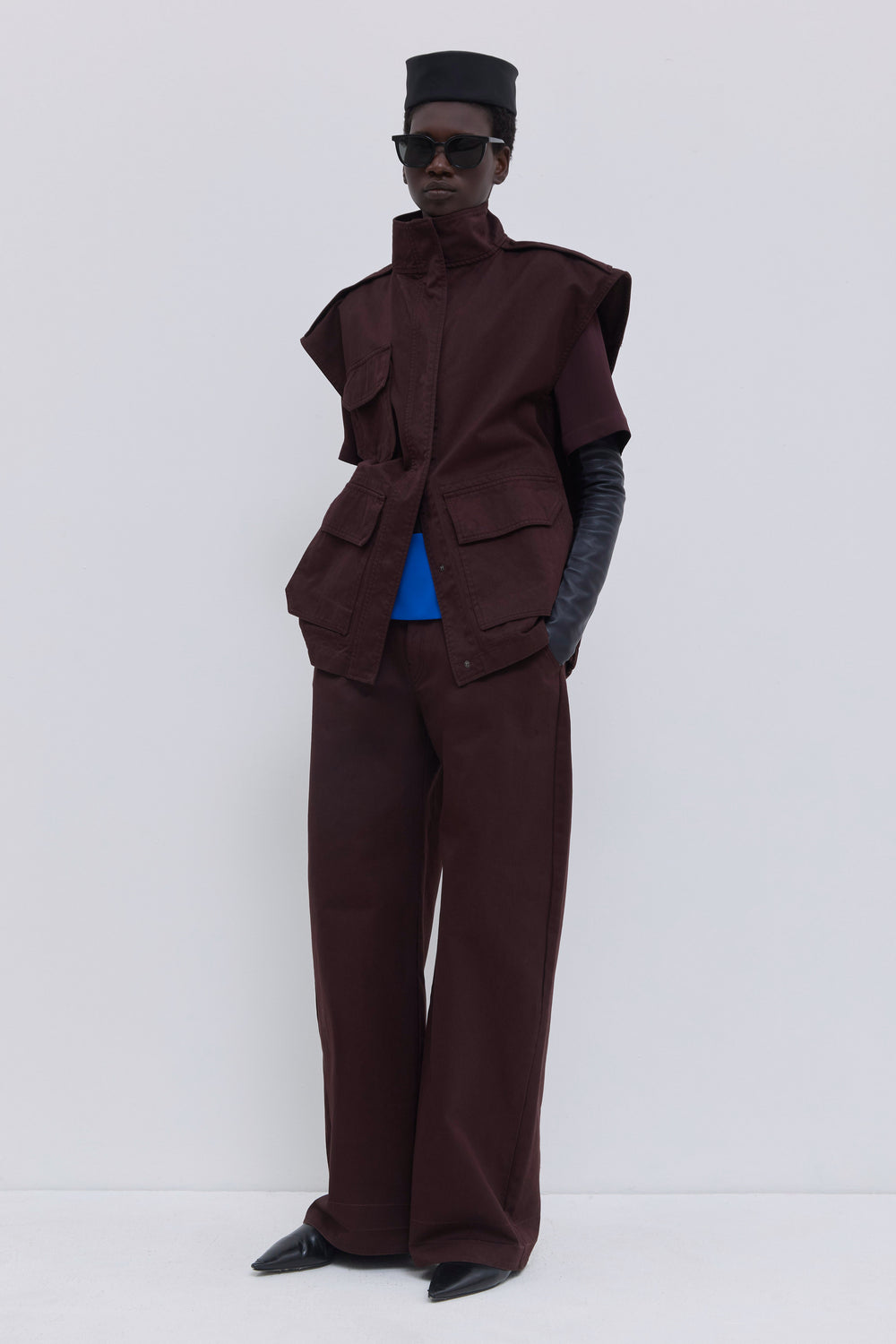 Luxury sleeveless jacket in plum organic cotton with structured silhouette, utility pockets and garment-dyed finish.