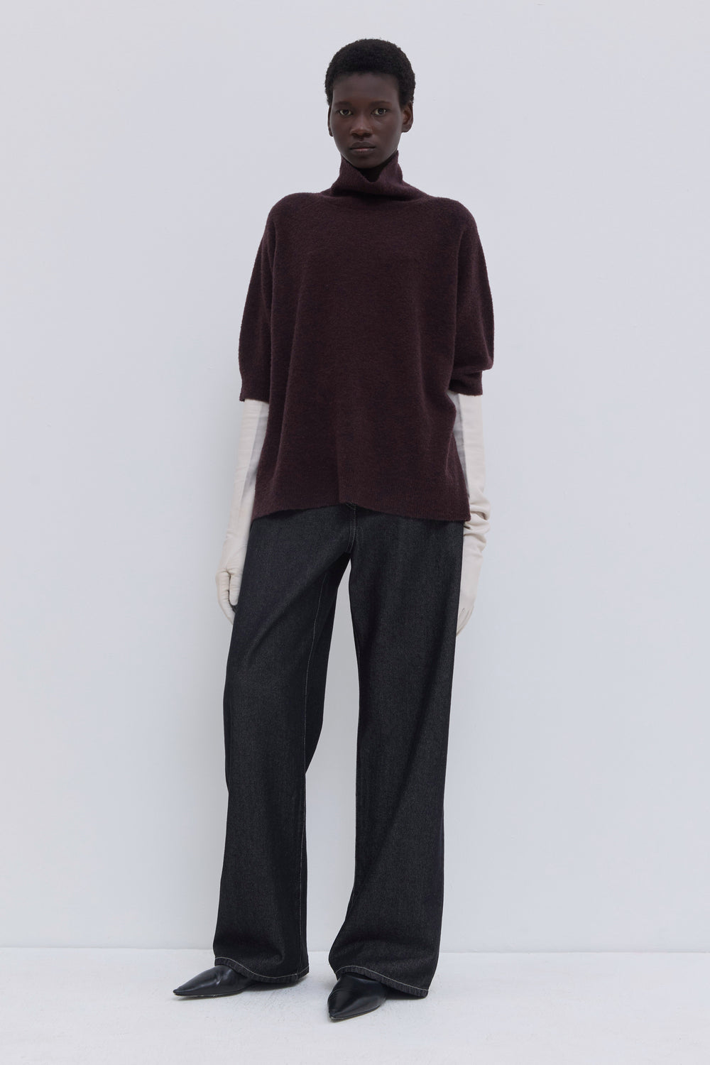 Side view of a relaxed-fit deep plum bouclé knit top with rolled turtleneck.