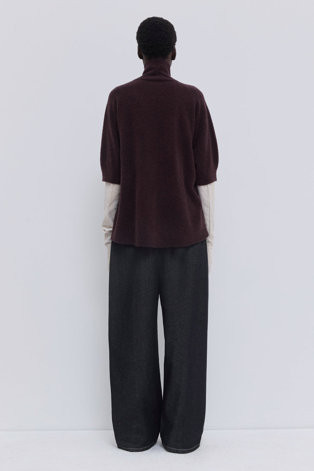 Back view of a deep plum oversized bouclé knit top with short sleeves.