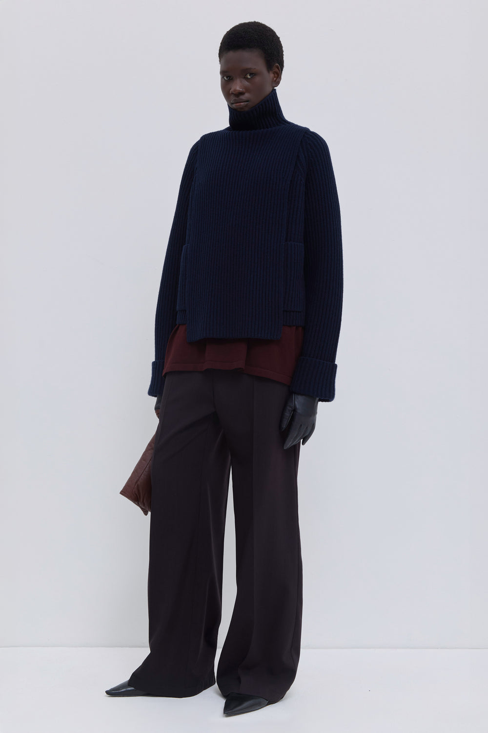 Dark marine ribbed merino wool and cashmere knit bib styled under a matching ribbed cardigan with wide-leg tailored trousers.