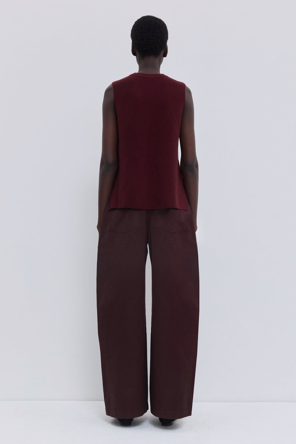 Back view of a garnet wholegarment knit top with clean minimalist silhouette.