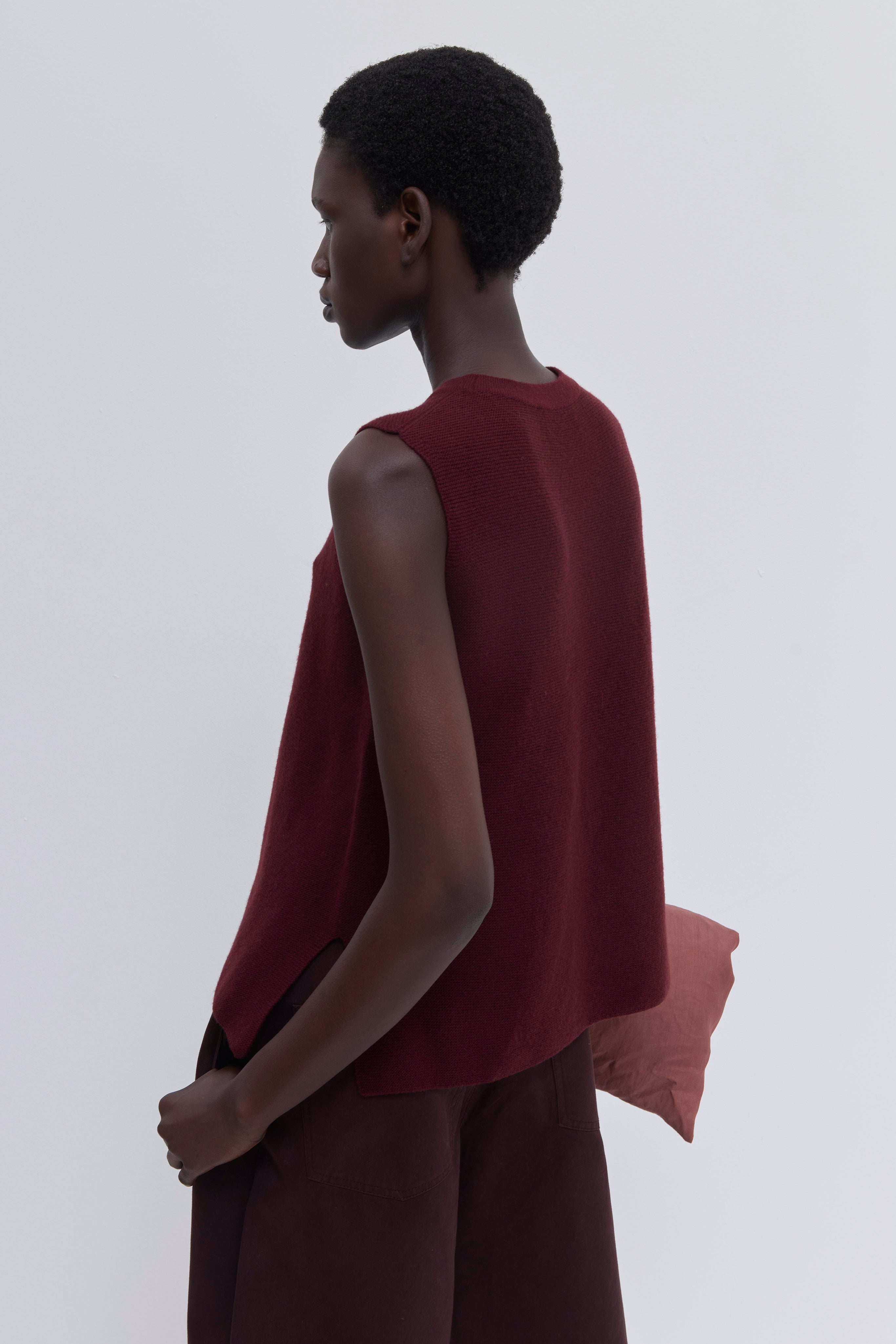 Luxury garnet sleeveless knit top with side slits and seamless construction.