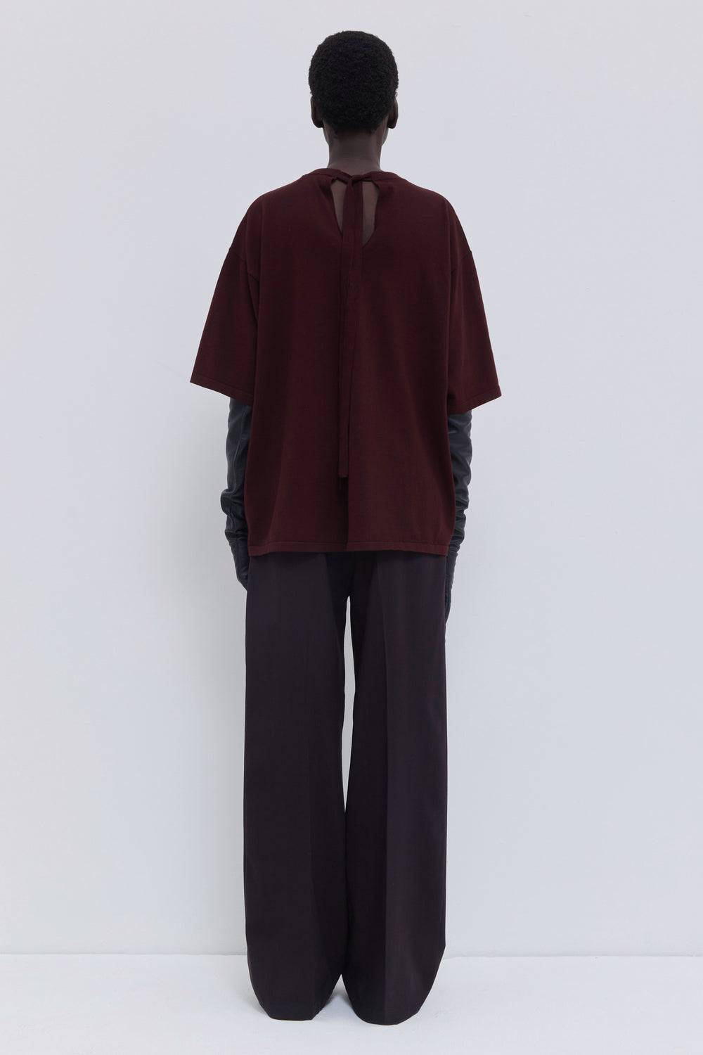 Back view of a plum cotton T-shirt featuring an open back with strap closure.