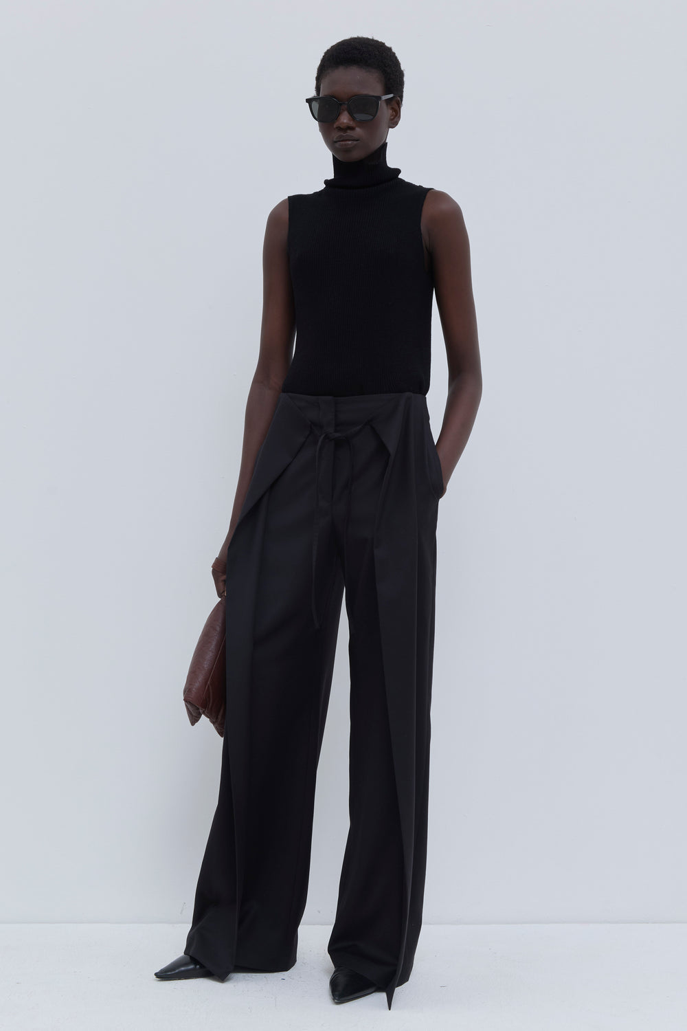 Side view of the Paire wide-leg trousers in black with deep pleats and wide legs.