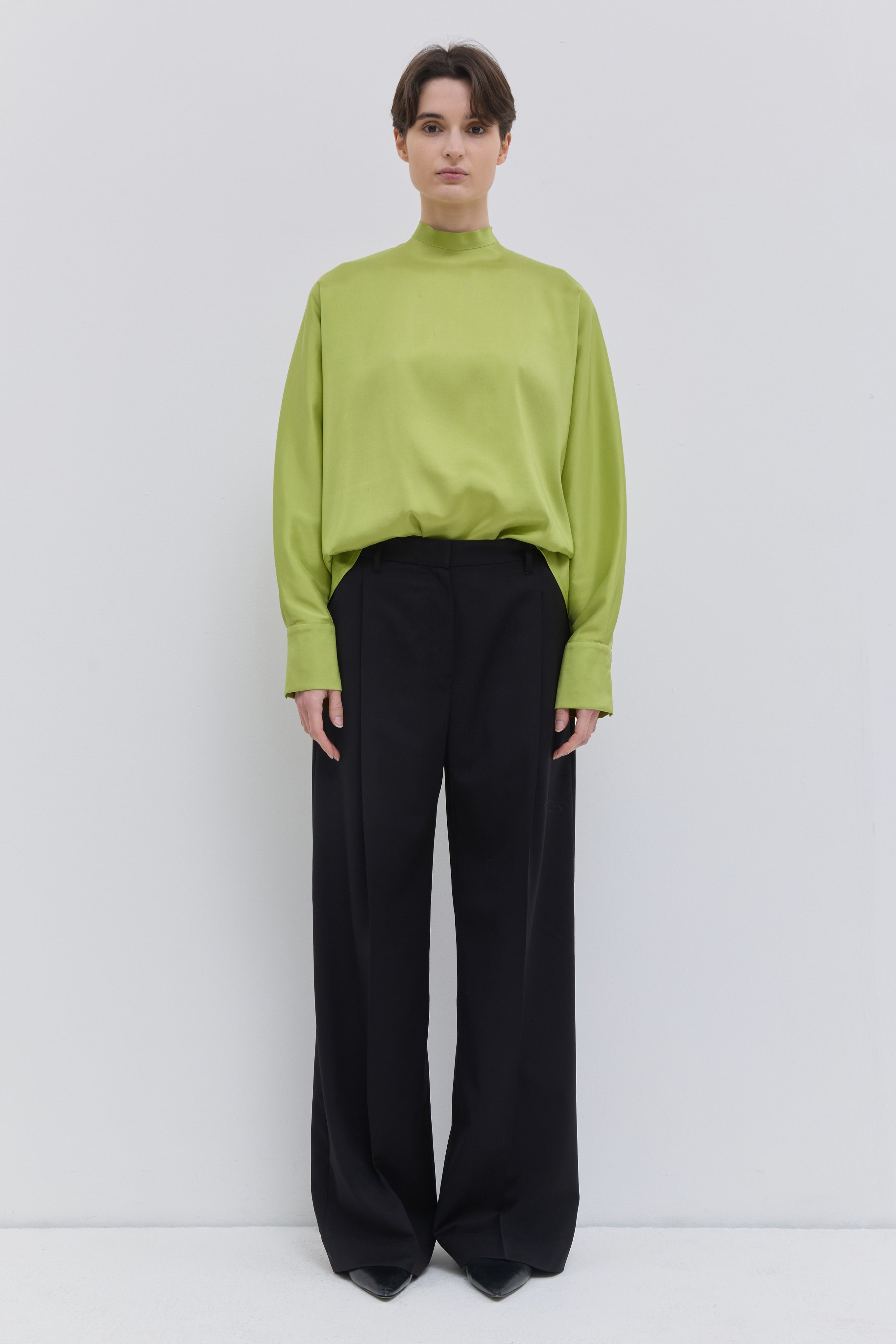 Model wearing black Italian wool wide-leg trousers with front crease and tailored fit by Christian Wijnants.