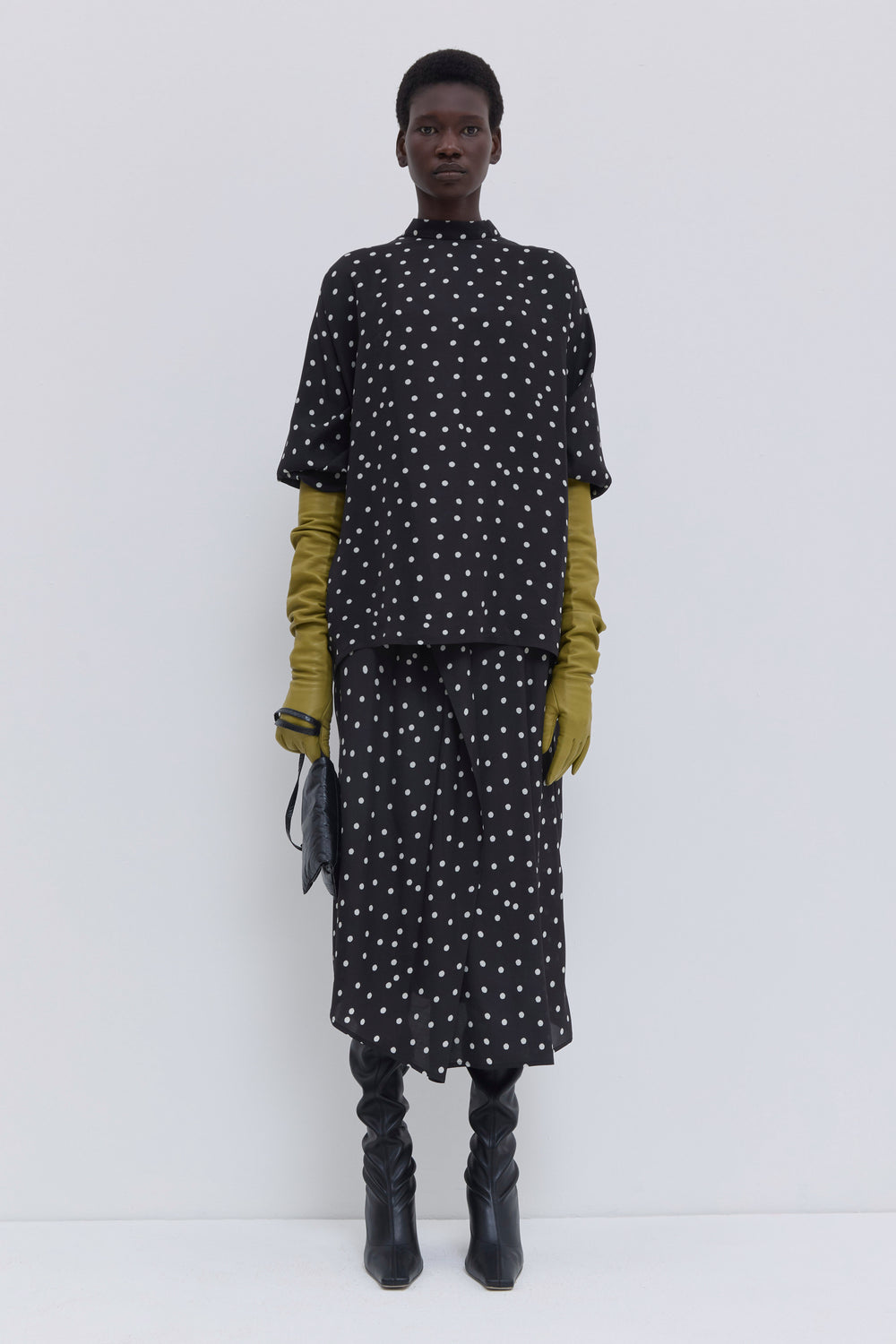 Model wearing a black lady bug print draped skirt with elastic waistband and asymmetric hem by Christian Wijnants.