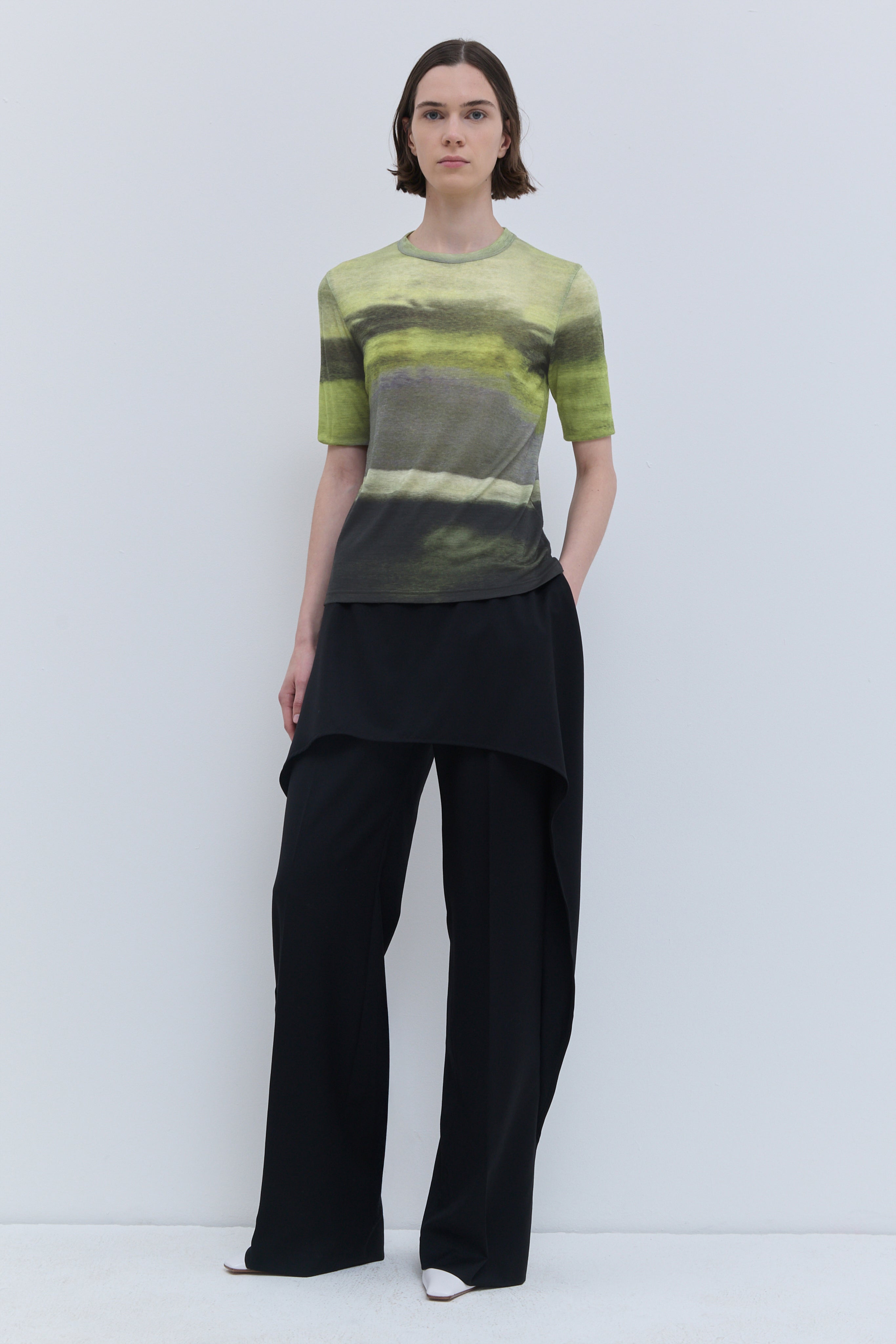 Model wearing the Tampi short-sleeve wool jersey top in Day Break print, featuring a close-fitting silhouette and abstract green landscape-inspired print.