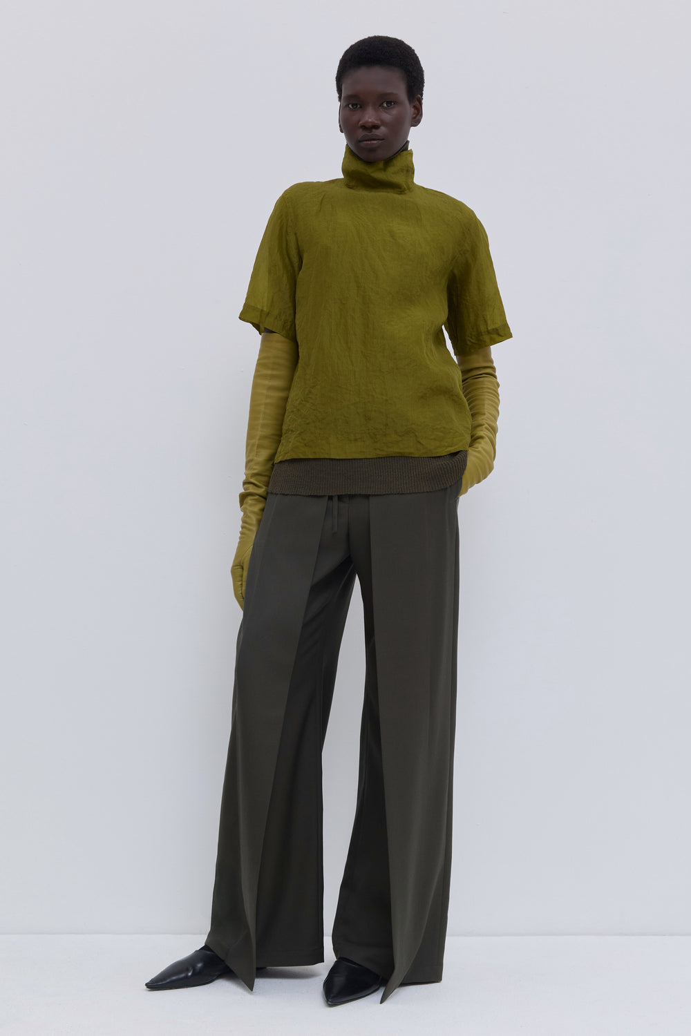 Side view of the Tapulo high-neck top in olive silk organza featuring a button closure and handcrafted crinkled finish.